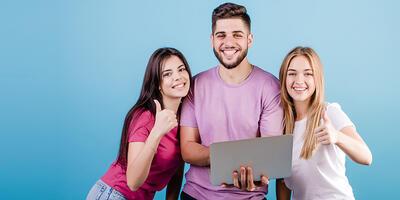 drei junge Menschen, stehend, Mann in der Mitte hält Laptop in der Hand